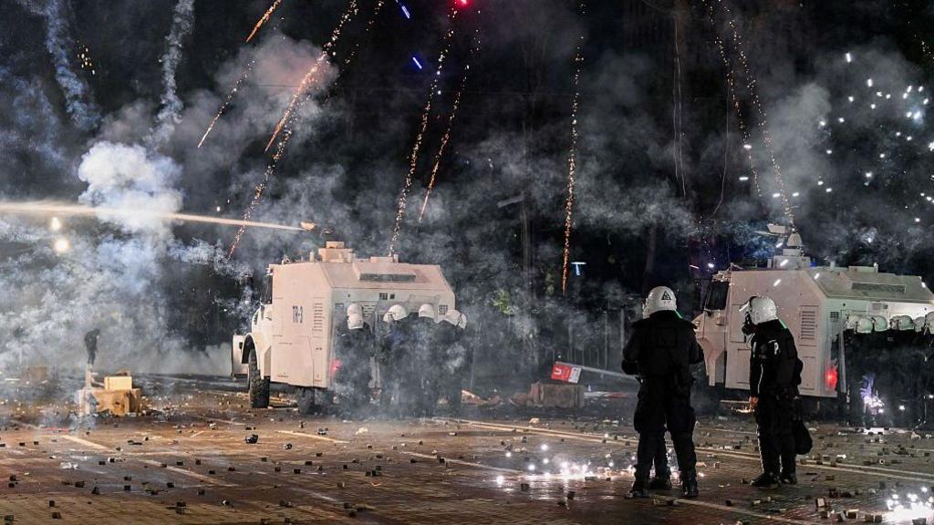 Fireworks explode near a police water cannon as protests break out in Tirana