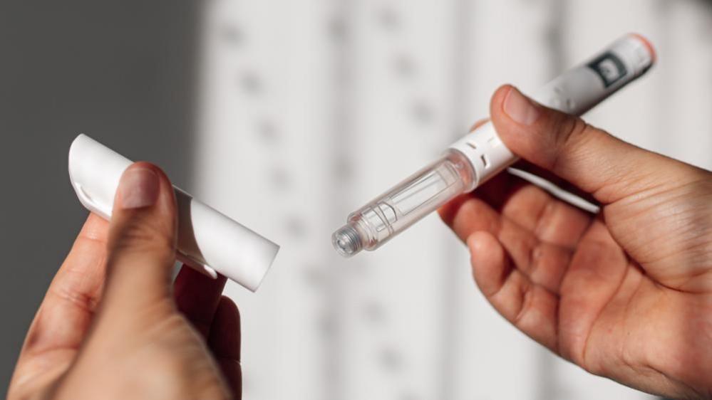 Woman’s hands holding a weight‑loss injection pen